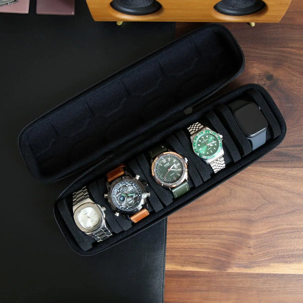 A black leather watch travel case organizer holding several wristwatches and a smartphone on a wooden surface.