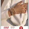 Gros plan d'une main portant un élégant collier imitation perles contre un blazer blanc.