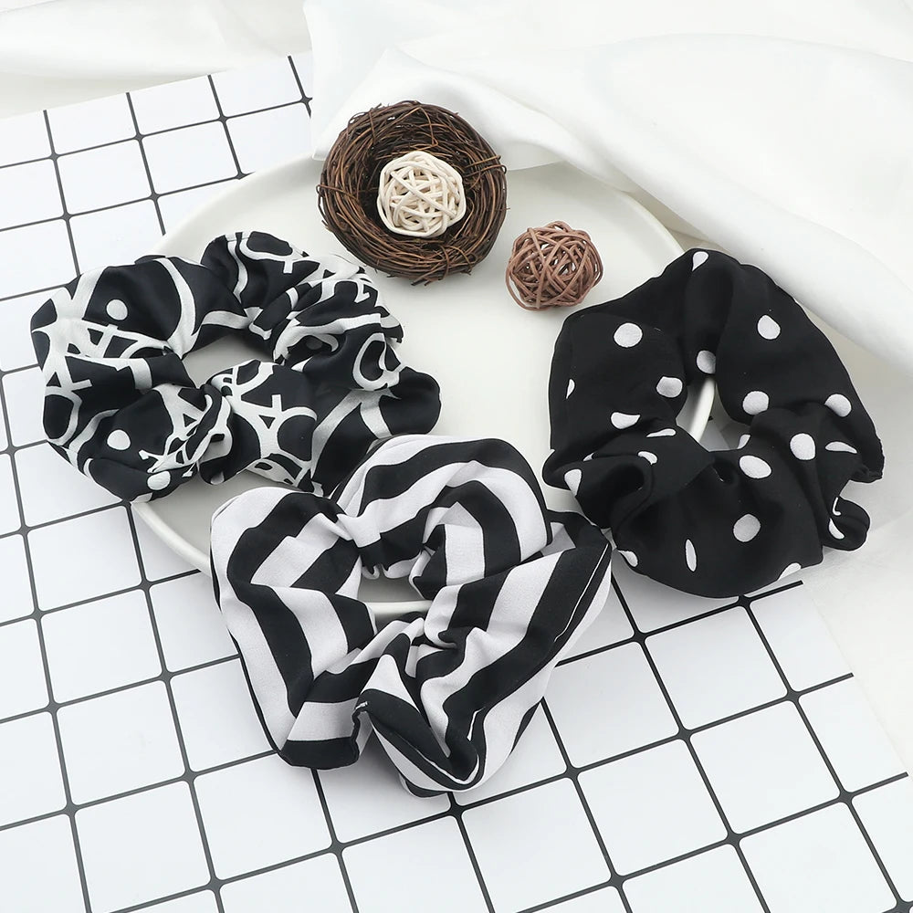 A black and white polka dot fabric scrunchie headband is displayed next to a natural fiber ball.