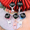 A set of black LED digital keychain watches with silver and pink charms displayed against a red pleated background.