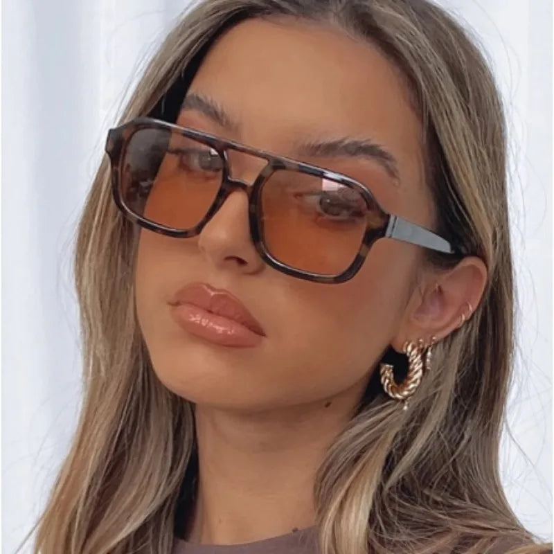 Nahaufnahme einer Frau mit Vintage-Pilot-Sonnenbrille mit orangefarbener Linse und Doppelbrücke