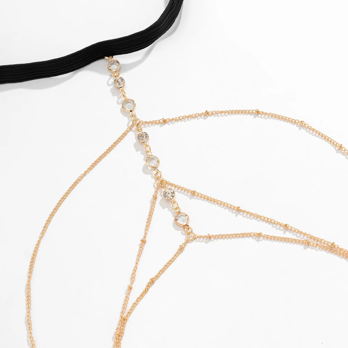 Gold crystal body chain jewelry featuring delicate chains and a black cord.