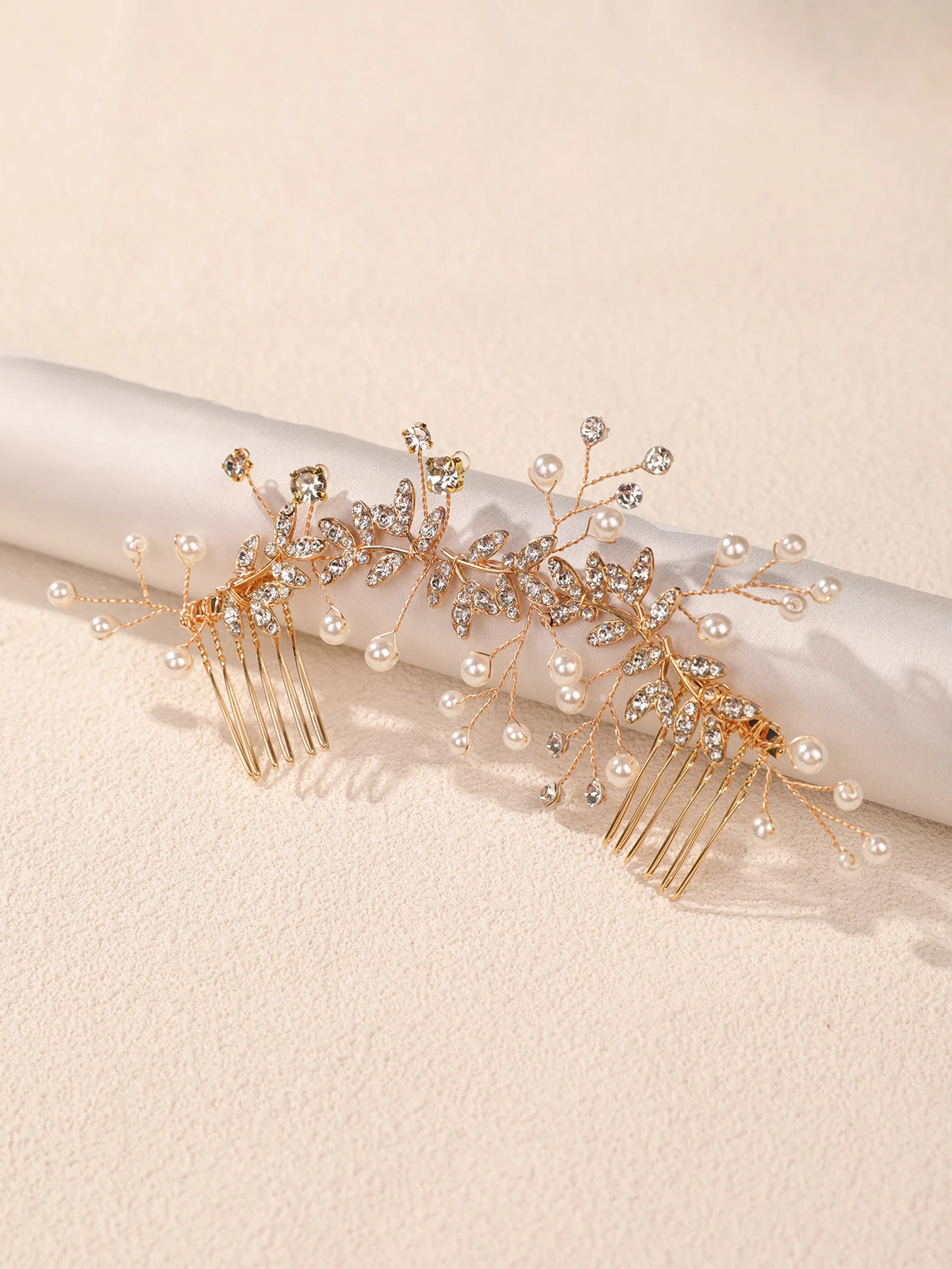 A delicate gold leafed crystal hair comb with pearl accents displayed on a white surface.