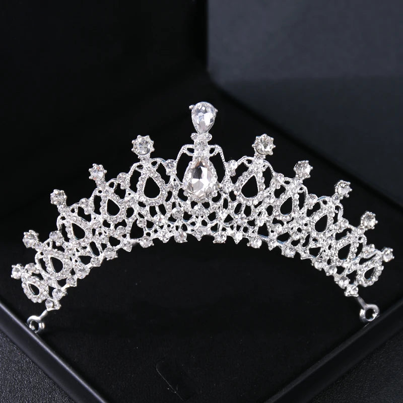 Tiare et couronne en strass cristallins sur une surface sombre.