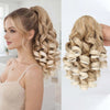 A woman shows off a long blonde hair extension styled in an elegant, voluminous curly ponytail using a claw clip.