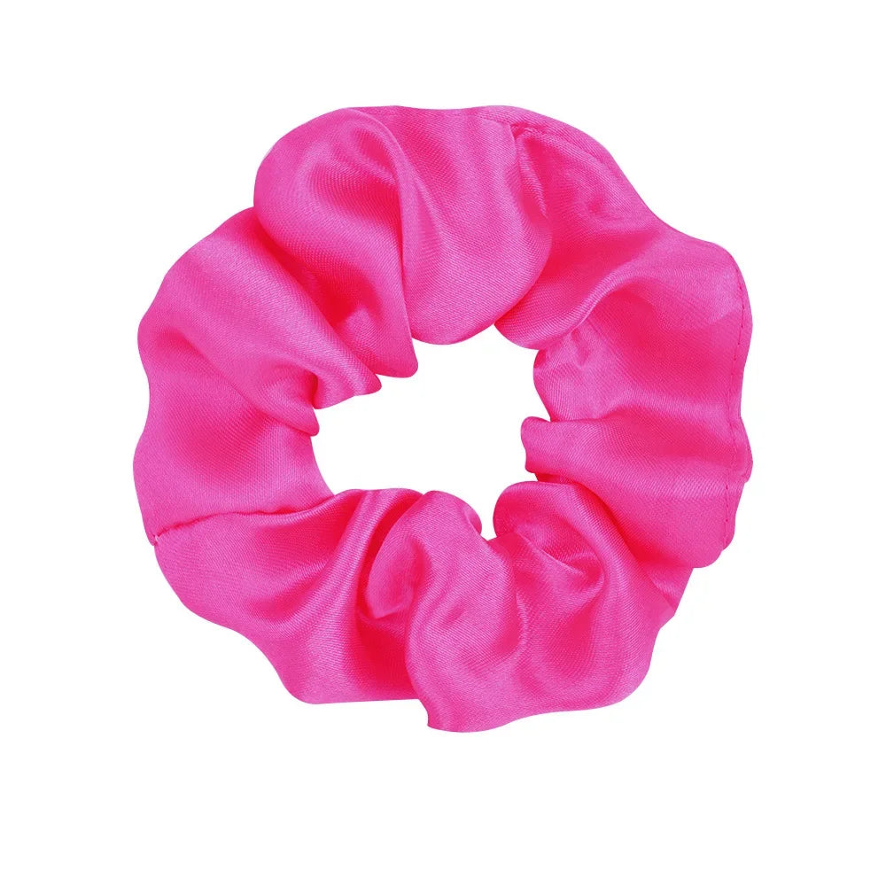 A vibrant pink satin scrunchie tied in a gathered fabric loop.