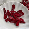 A collection of red star-shaped snap clips for hair and barrettes displayed on a white plate.
