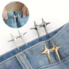 A pair of silver and gold star-shaped decorative waist buckle buttons shown on a denim fabric.