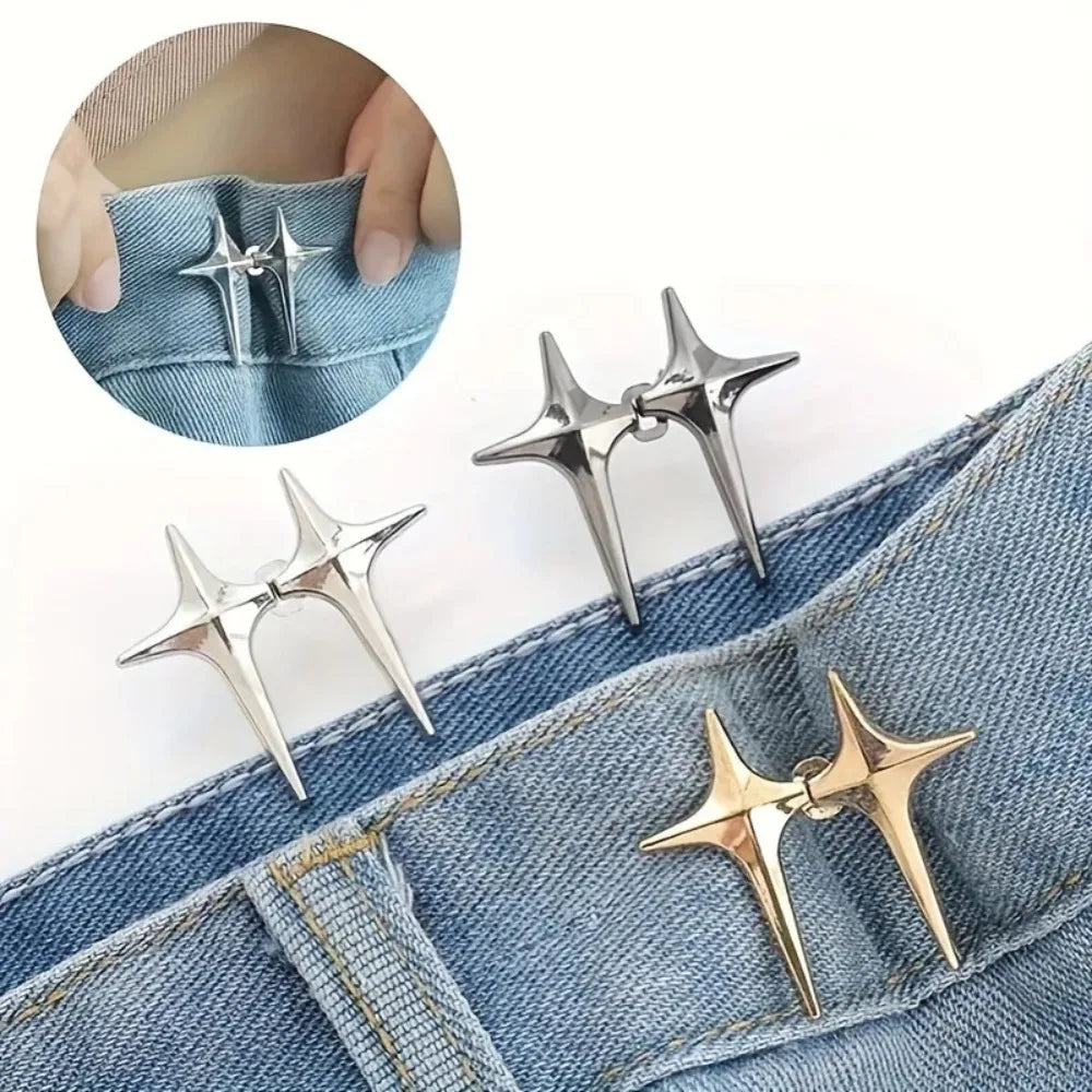 A pair of silver and gold star-shaped decorative waist buckle buttons shown on a denim fabric.