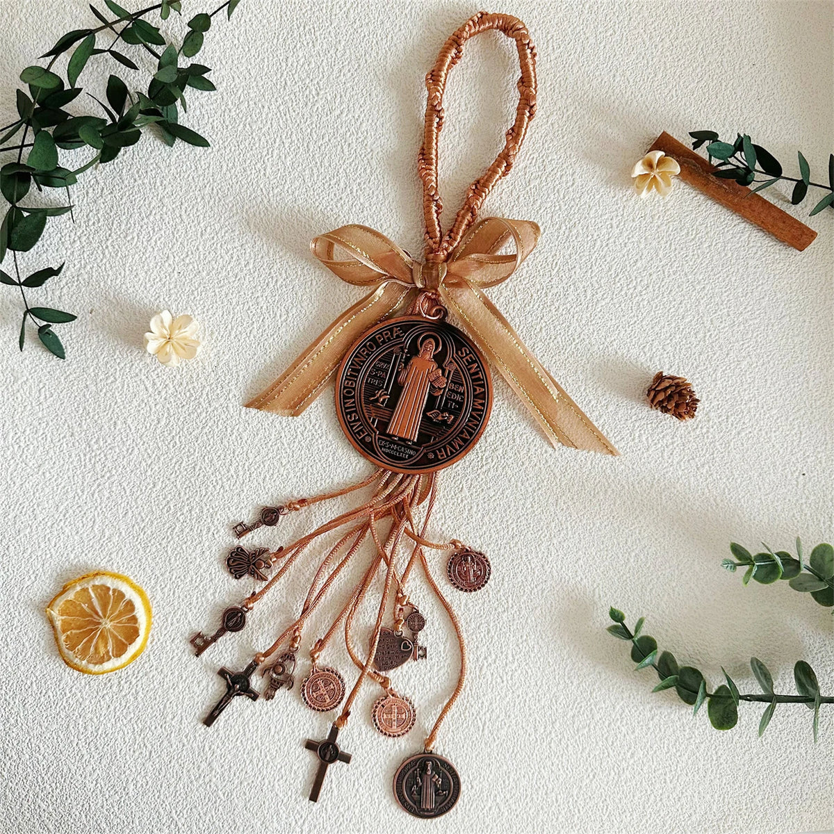 A set of brown leather and bronze charms featuring a saint figure, crucifixes, and other religious symbols on a light backgro
