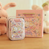 A pink decorative tinplate candy box with a carrying loop sits in front of a larger pink wedding-themed box and a fluffy rabb
