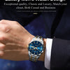 A close-up of a luxury men's watch with a blue luminous dial and silver bracelet worn on a wrist.