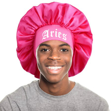 A young man wearing a pink satin sleep bonnet with an Aries wrap band.