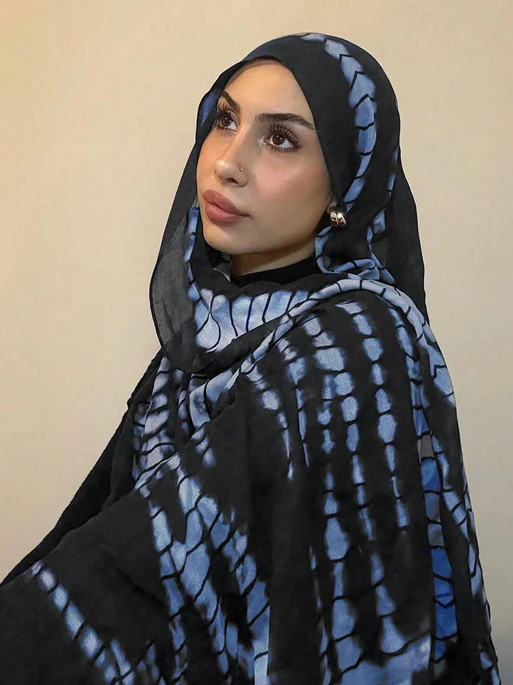امرأة ترتدي حجابًا منقوشًا بطبعة أزرق وأسود متداخلة.