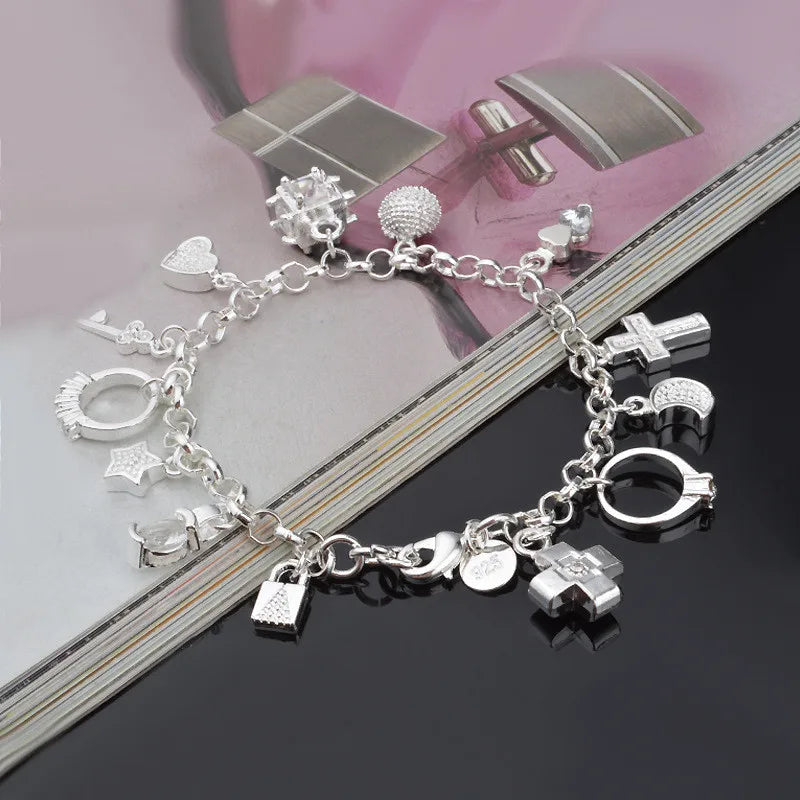 A silver geometric charm bracelet featuring various charms including crosses, stars, and rings.