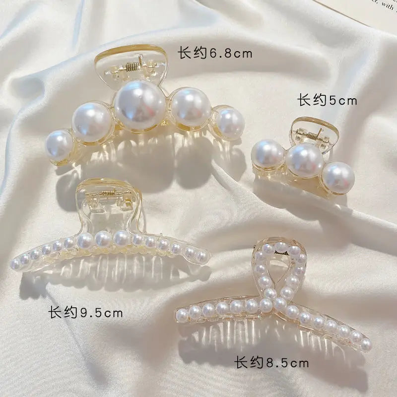 Clear simulated pearl hair claws in various lengths and styles displayed on a white fabric.