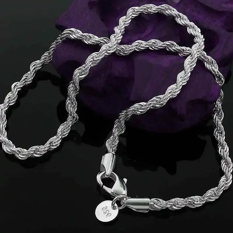 A silver rope charm necklace with a pendant is displayed against a dark purple background.