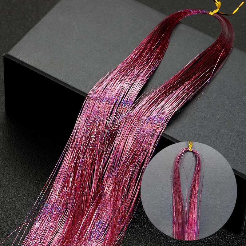 Long, vibrant pink and purple glitter hair extensions displayed on a black box.