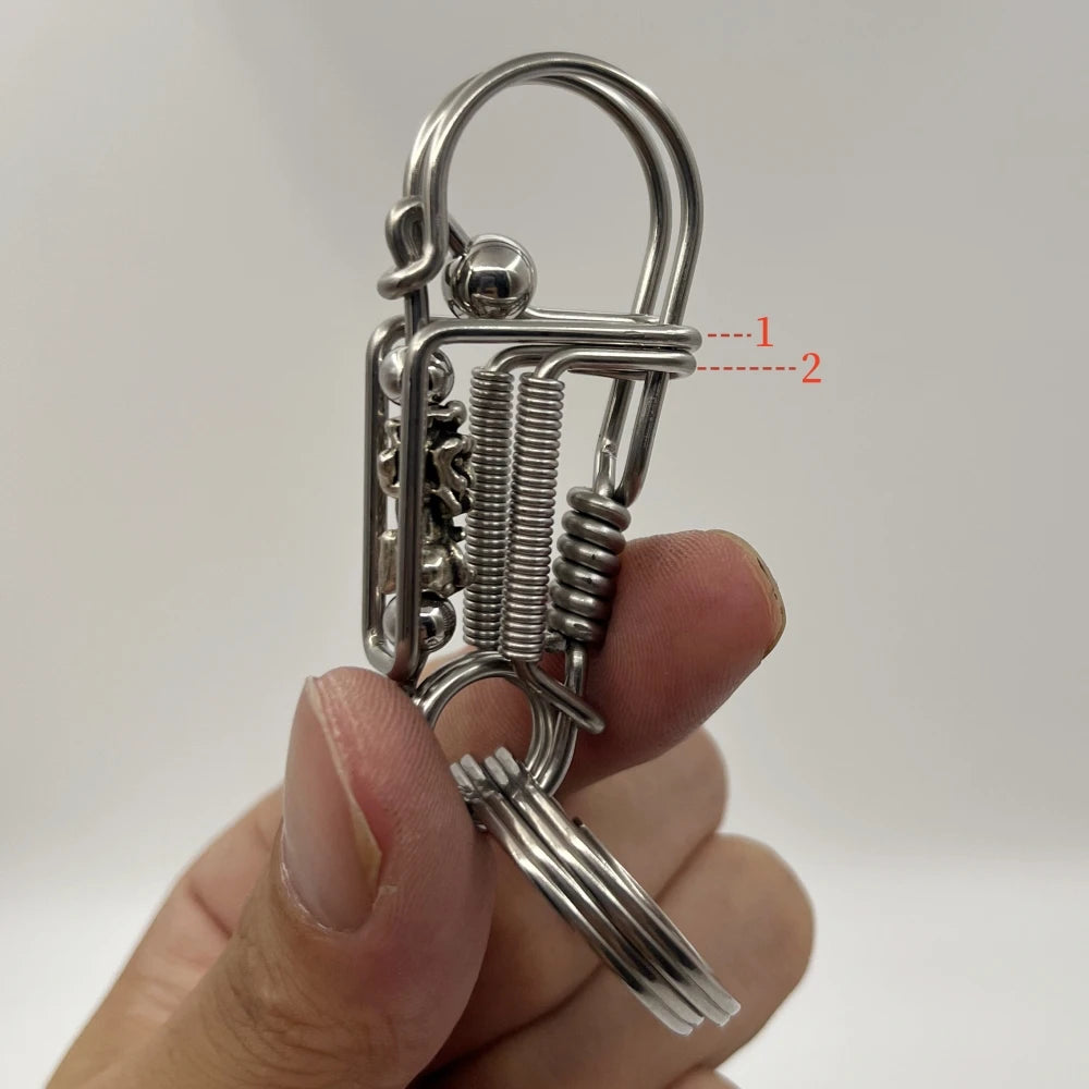 Un porte-clés mécanique en acier inoxydable avec mécanisme à ressort et boucle, tenu dans la main d'une personne.