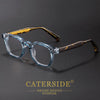 A pair of clear acetate retro square anti-blue light eyewear with gold accents resting on a dark surface.