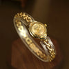 A gold-toned quartz fashion wristwatch on a clear strap, viewed from above.