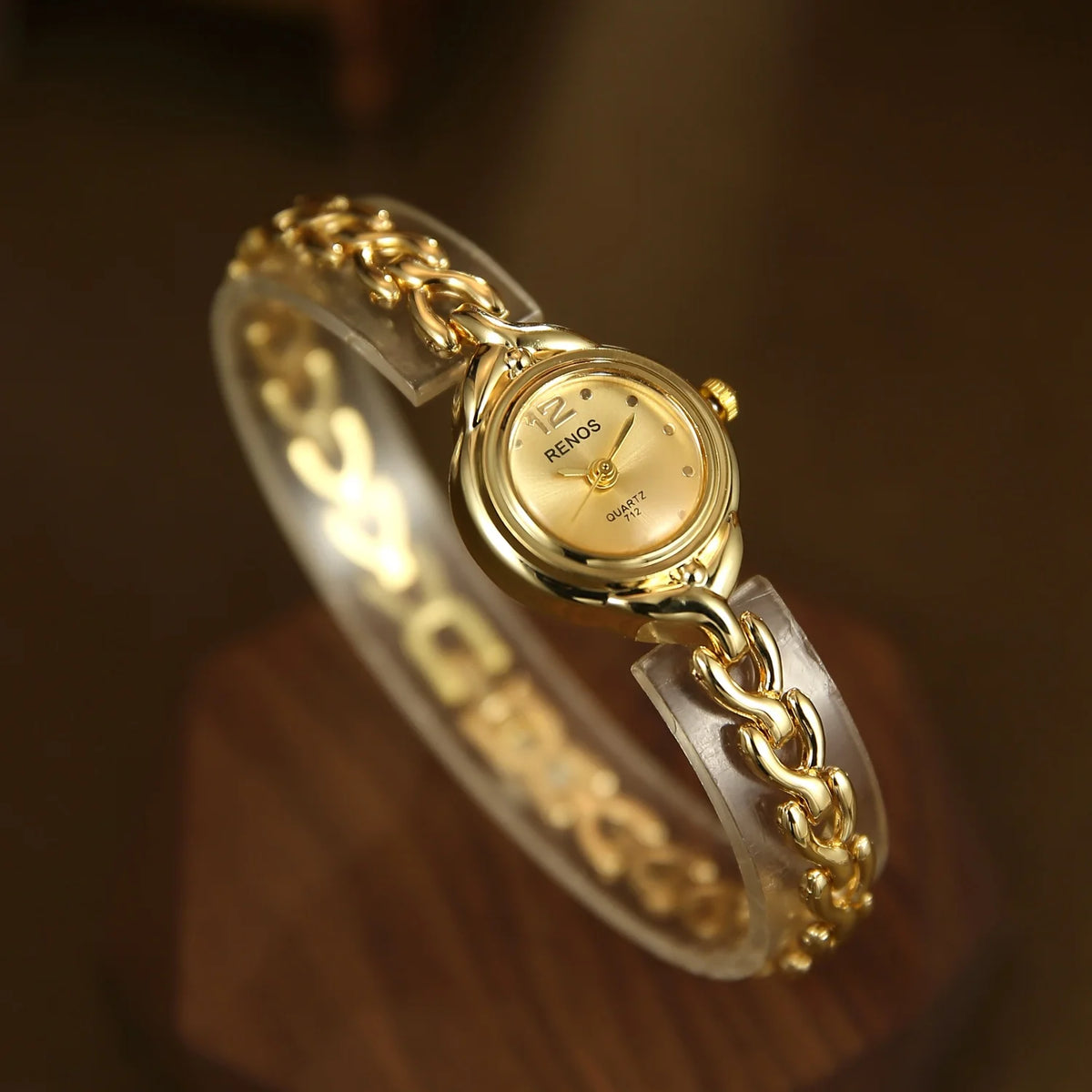 A gold-toned quartz fashion wristwatch on a clear strap, viewed from above.