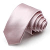 A stack of a dusty rose satin neck tie folded neatly on a white surface.