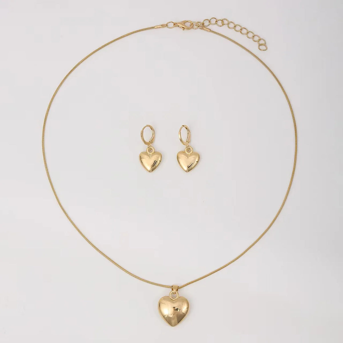 A delicate gold heart necklace and matching earring set displayed against a white background.