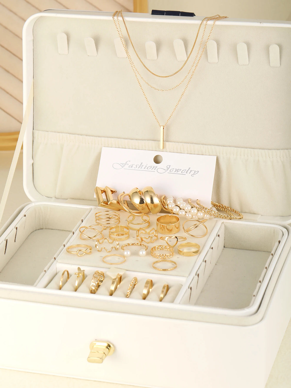 Collection de bijoux géométriques dorés bohèmes : colliers, bagues et boucles d'oreilles, présentés dans une boîte à bijoux b