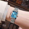 A close-up of an elegant gold plated quartz fashion watch with a blue face and silver bracelet worn on a wrist.