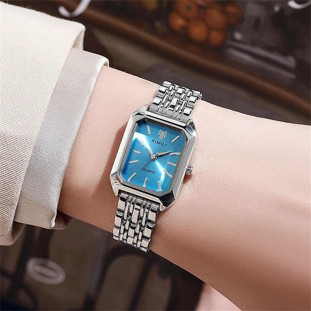 A close-up of an elegant gold plated quartz fashion watch with a blue face and silver bracelet worn on a wrist.