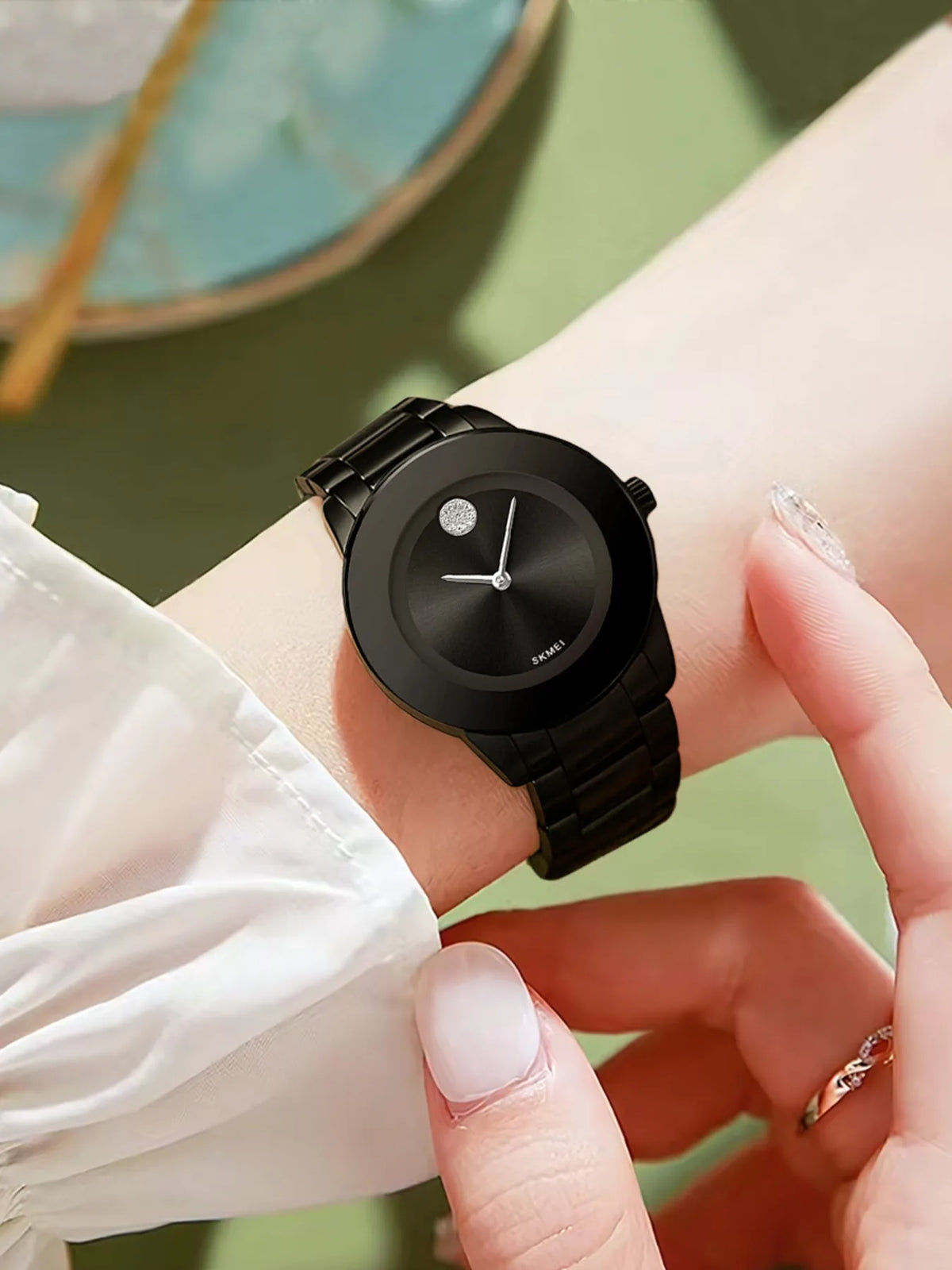 Primer plano de un reloj de cuarzo negro de pulsera, con una mano sosteniéndolo.