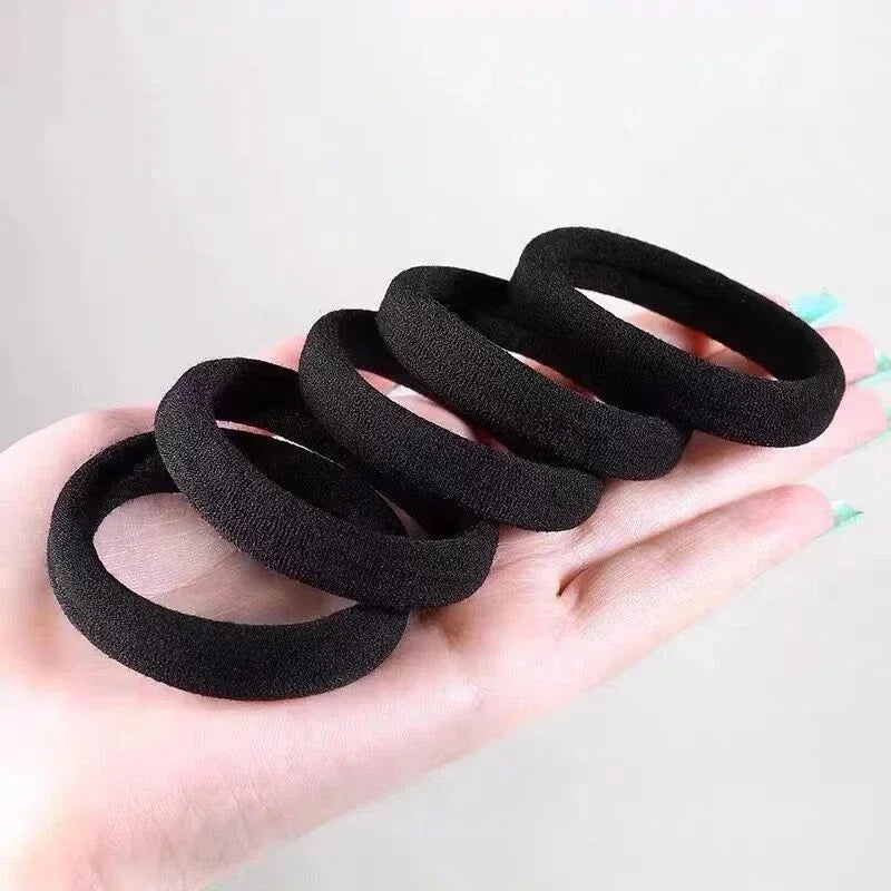 Eine Hand hält eine Stapel schwarze elastische Haargummis für Pferdeschwänze.