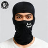 Un hombre vistiendo una balaclava de malla negra transpirable con un diseño de cara blanca goteando.