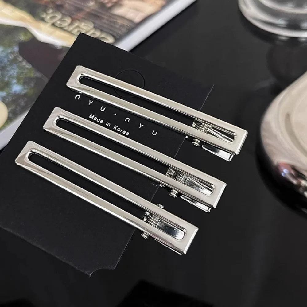 A set of vintage silver Y2K metal hair clips with 'Made in Korea' engraving displayed on a black card.