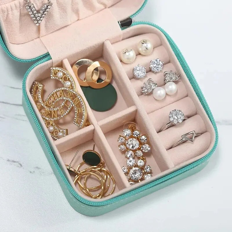 A pink leather jewelry travel organizer box filled with various gold and silver rings, earrings, and necklaces.