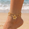 Gold bohemian starfish conch anklet worn on a person's ankle near the ocean.