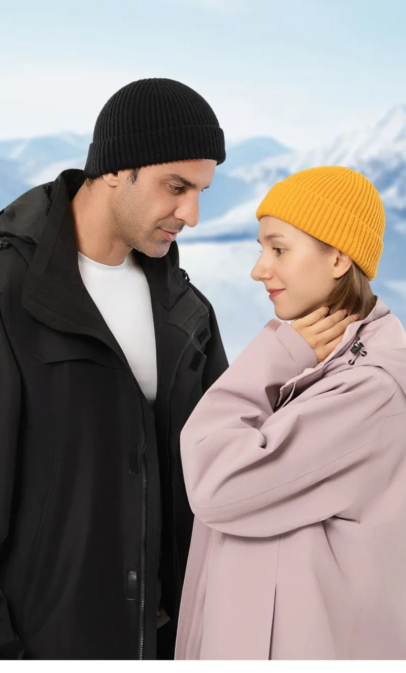 A man and a woman looking at each other, both wearing warm knitted beanie caps.