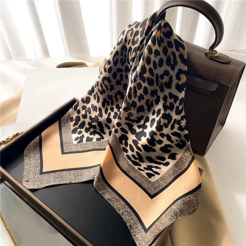 Luxuriöser Leopardenmuster-Seiderschal über einer dunklen Lederhandtasche.