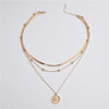 Gold-toned stainless steel necklace featuring a cross pendant and layered chains.