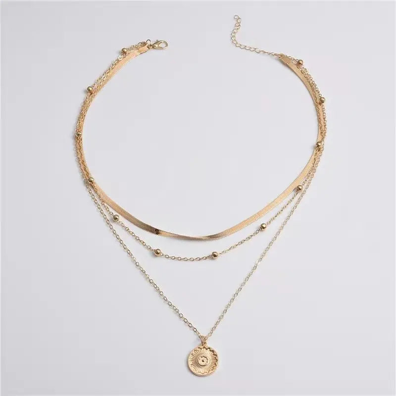 Gold-toned stainless steel necklace featuring a cross pendant and layered chains.