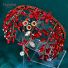 A sparkling rhinestone bridal hair hoop featuring red leaves and jewels on a clear stand.