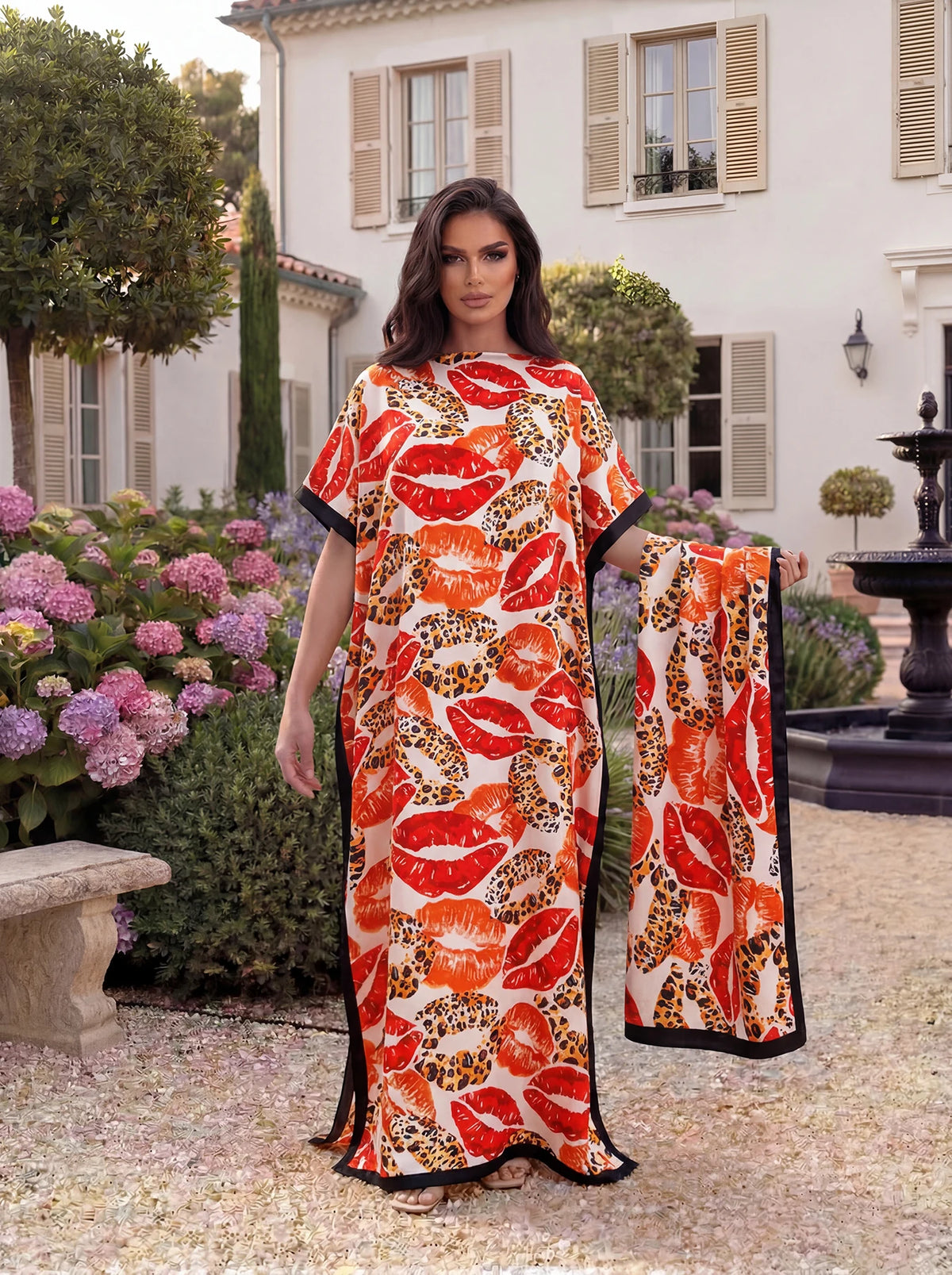 Eine Frau modelliert ein orange-leopardiges Satin-Abaya-Schal-Set im Freien vor einem weißen Gebäude.