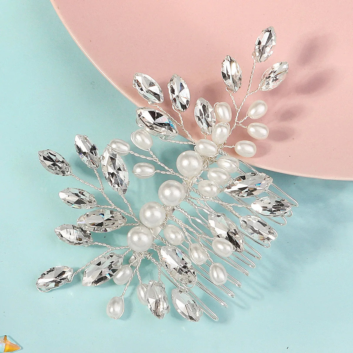 Pince à cheveux de mariage en cristal d'argent et perles sur une surface rose.