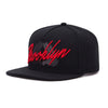 Black unisex adjustable snapback cap with red embroidered text