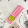 Pink hairband with a lime green dot, set against a white background with natural elements.