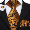 A close-up of a men's silk jacquard tie featuring an ornate gold and black pattern worn with a black suit jacket.