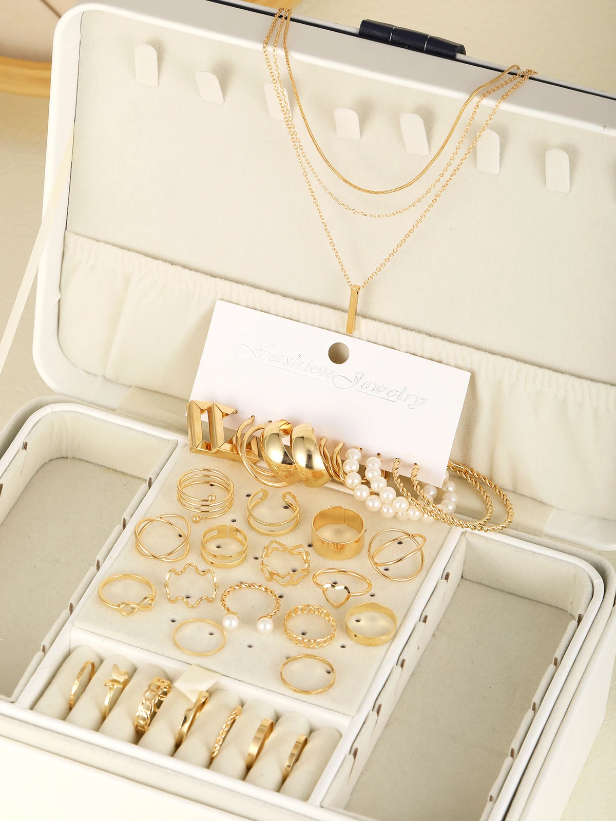 Collection de bijoux géométriques dorés bohèmes, colliers, bagues et boucles d'oreilles, présentés dans une boîte à bijoux bl