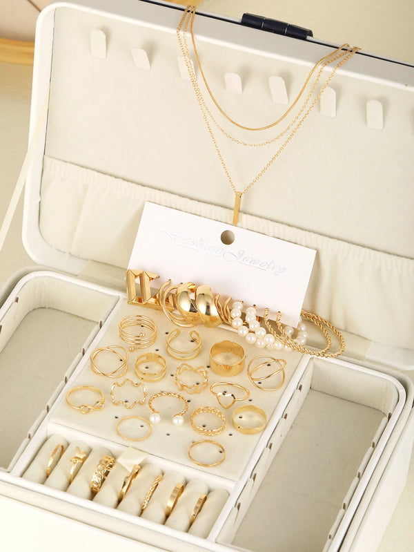A collection of boho gold geometric jewelry including necklaces, rings, and earrings displayed in a white jewelry box.