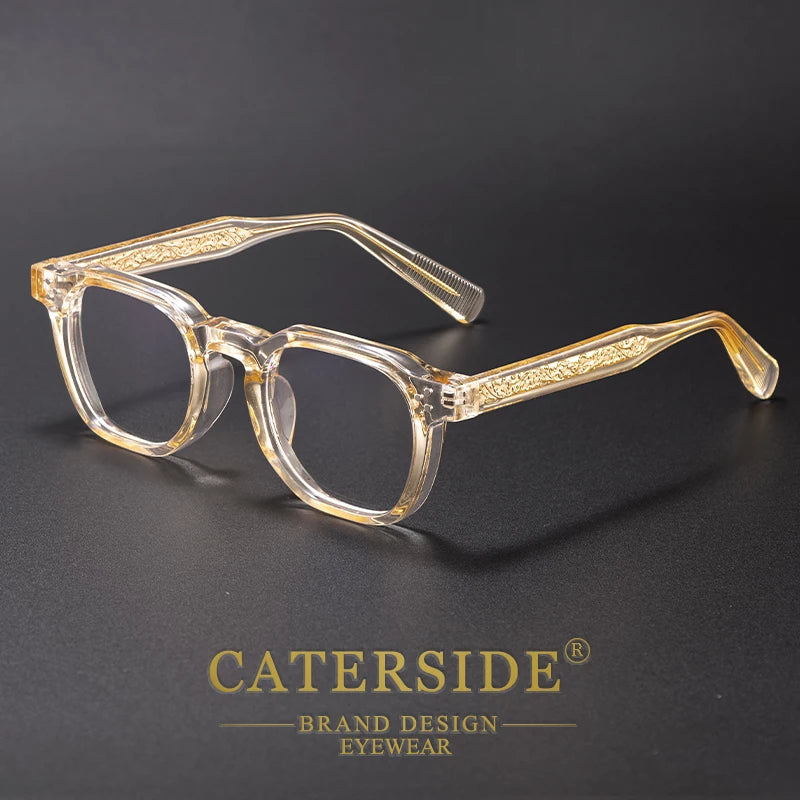 Clear acetate retro square anti-blue light eyewear with gold detailing resting on a dark surface